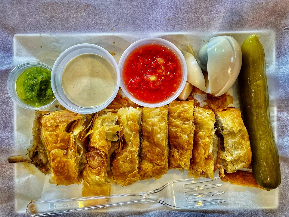 בורקס חתוך מוגש בליווי ביצה, מלפפון חמוץ, טחינה, רסק עגבניות וחריף ב"בורקס עמיקם"