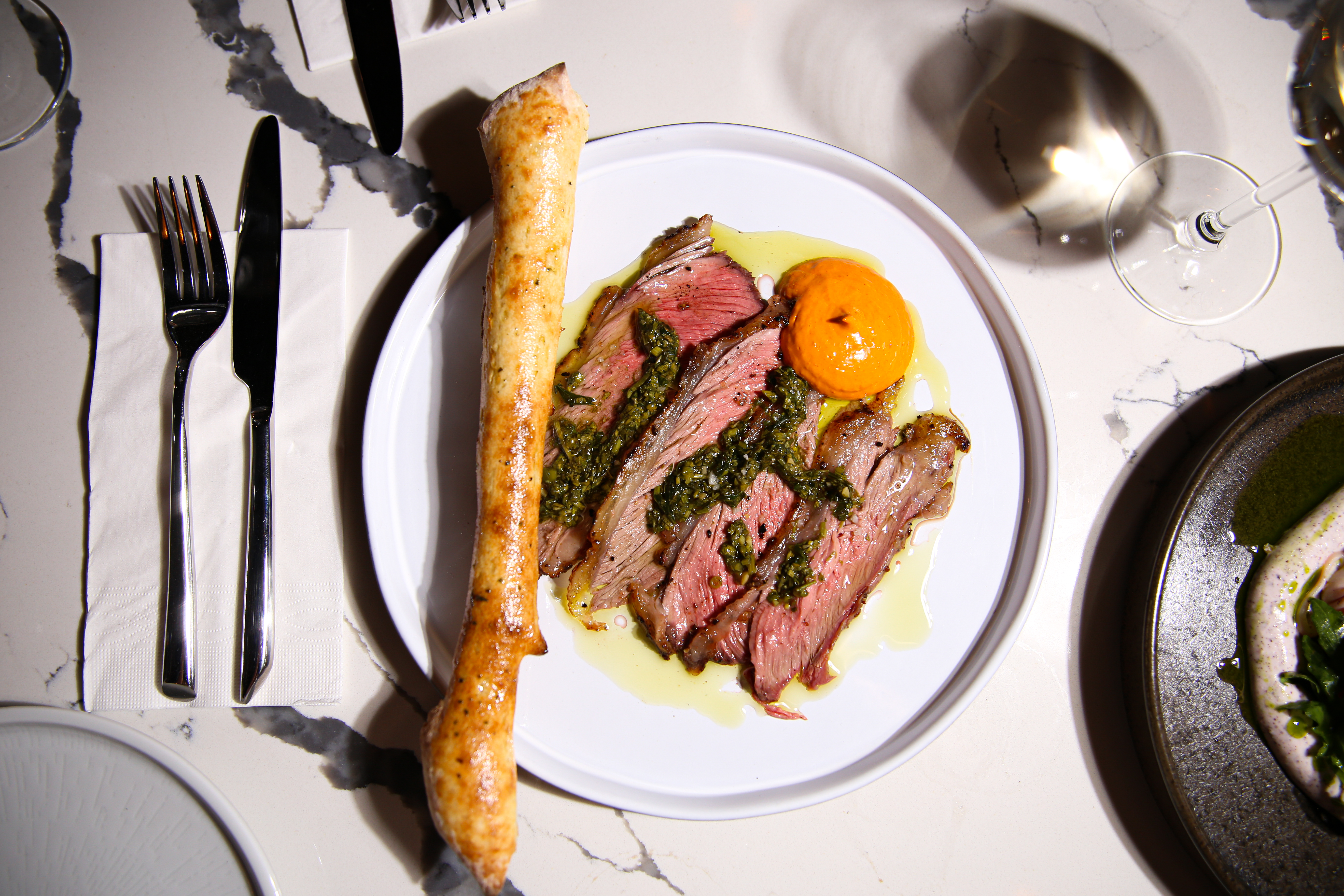 מנת בשר מוגשת על צלחת לבנה בליווי מאפה במסעדת השף בצפון ל'אוסטריה