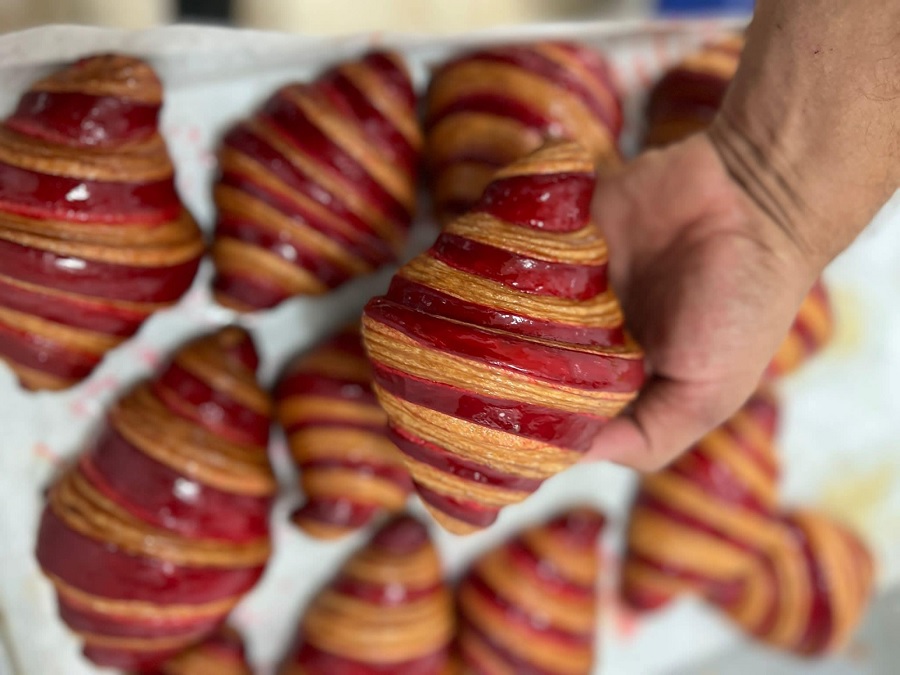 אדם מחזיק בקרואסון עם מילוי אדום